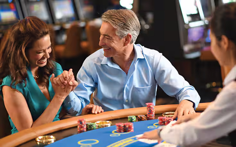 Couple sittng at casino table on Allura cruiseship